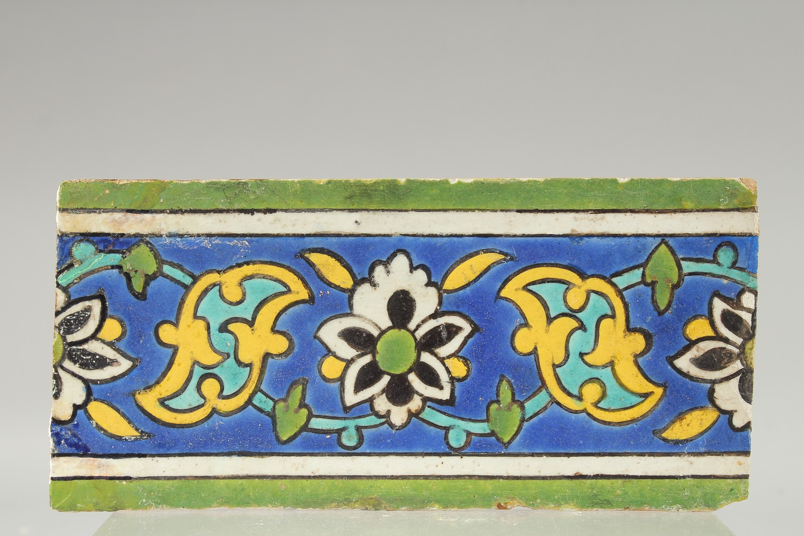 A FINE 17TH CENTURY PERSIAN SAFAVID GLAZED POTTERY TILE, 23cm x 11cm.