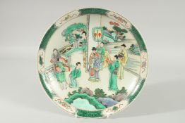 A CHINESE FAMILLE VERTE PORCELAIN DISH, painted with figures in a courtyard scene, 29cm diameter.