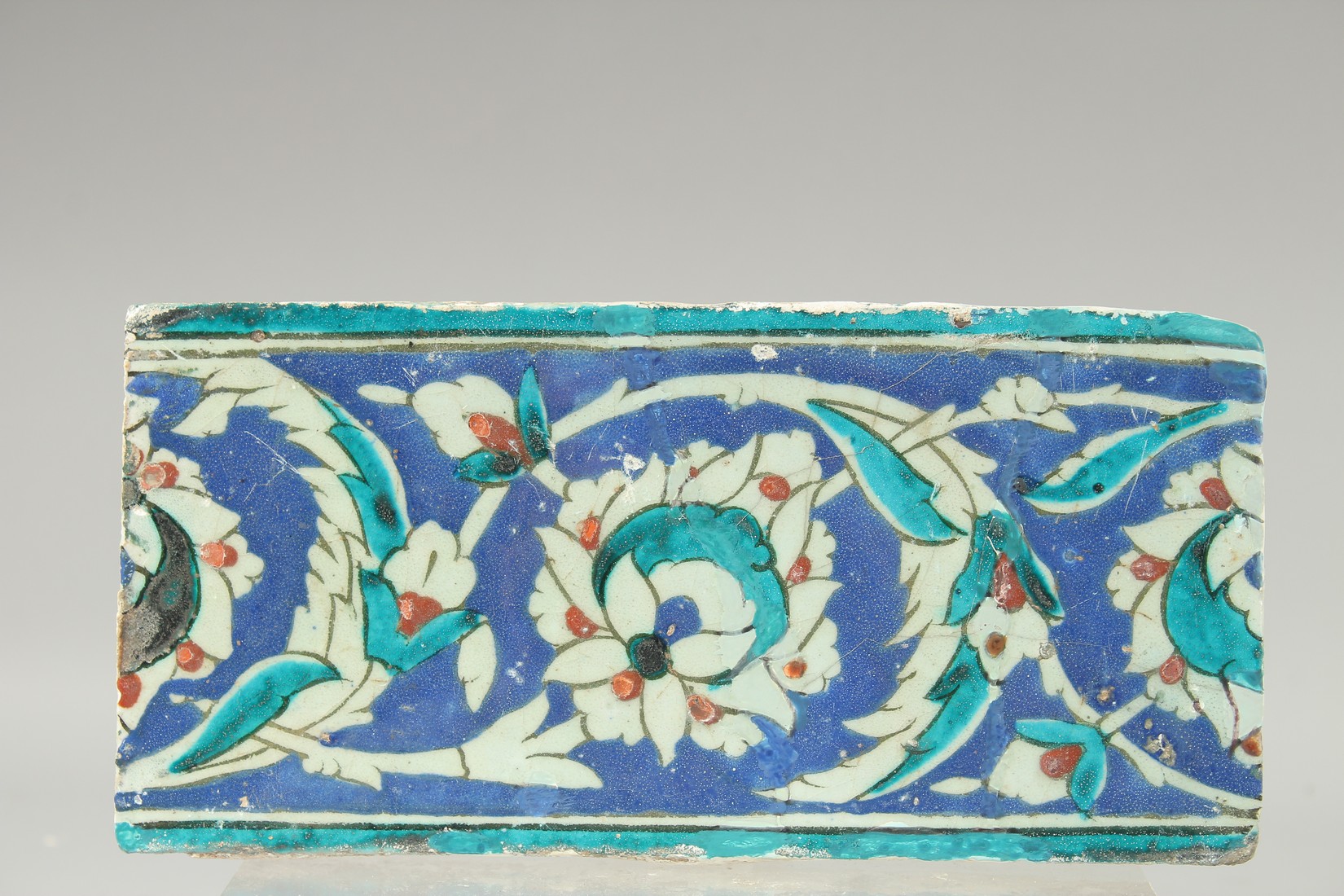 AN EARLY 17TH CENTURY OTTOMAN TURKISH GLAZED POTTERY BORDER TILE, 25cm x 12cm.