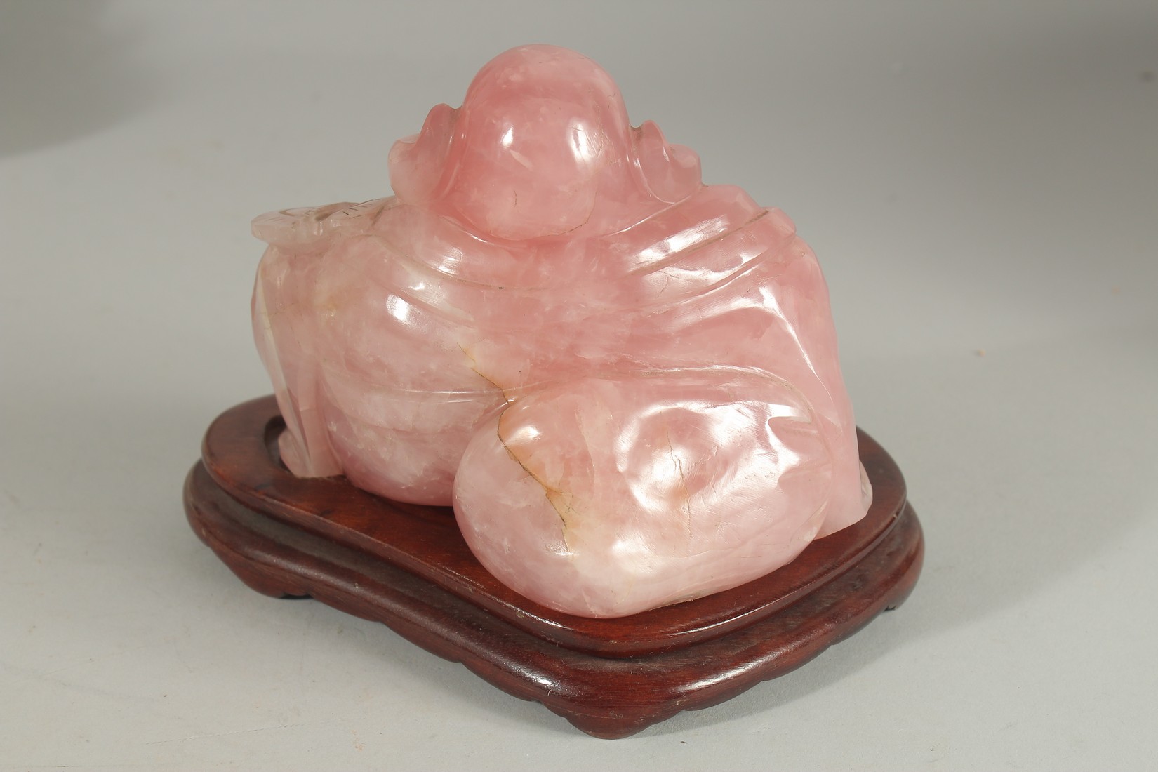 A CHINESE CARVED ROSE QUARTZ BUDDHA on wooden stand, 19cm wide overall. - Image 2 of 3