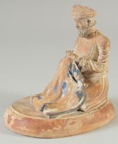 AN OTTOMAN TERRACOTTA SEATED FIGURE, on oval base, 14cm long.