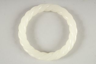 A WHITE JADE TWIST BANGLE 3.25ins diameter.