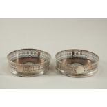 A PAIR OF GEORGE III SILVER CIRCULAR WINE COASTERS with wooden bases. 4.75ins diameter London 1773.