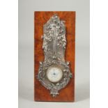 A SILVERED BAROMETER on a wooden base. 10ins x 4.5ins.