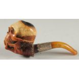 A MEERSCHAUM PIPE CARVED ON AS A HAND HOLDING A SKULL, 6cm long with silver band and curving amber