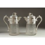 A GOOD PAIR OF SILVER PLATED AND GLASS CLARET JUGS with fruiting vine decoration. 10ins high.