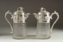 A GOOD PAIR OF SILVER PLATED AND GLASS CLARET JUGS with fruiting vine decoration. 10ins high.