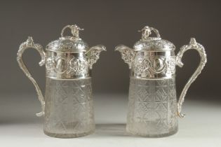 A GOOD PAIR OF SILVER PLATED AND GLASS CLARET JUGS with fruiting vine decoration. 10ins high.