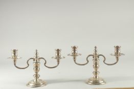 A PAIR OF SILVER SQUAT CANDLESTICKS with two branches, on arc bases. 6.5ins high by MAPPIN AND