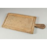 A PALE OAK CHOPPING BOARD. 21ins long