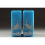 A GOOD PAIR OF AESTHETIC TURQUOISE GLASS, SQUARE VASES with storks in relief. 6.5ins high.