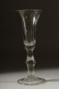 A GEORGIAN GLASS with long tapering plain bowl, knop to the stem. 7ins high.