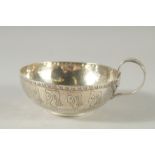 A CIRCULAR SILVER BOWL engraved with heads, with a handle. 4.5ins diameter. Chester 1904. Weight: