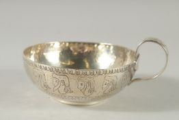 A CIRCULAR SILVER BOWL engraved with heads, with a handle. 4.5ins diameter. Chester 1904. Weight: