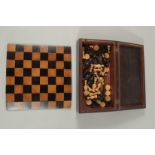 A TRAVELLING CHESS BOX AND FOLDING CHESS BOARD and chess pieces.