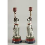 A PAIR OF PORCELAIN DOG CANDLESTICKS. 13ins high.