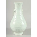 A Chinese celadon glazed moulded pottery balister shaped vase with lion mask handles. 11ins high.
