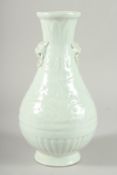 A Chinese celadon glazed moulded pottery balister shaped vase with lion mask handles. 11ins high.