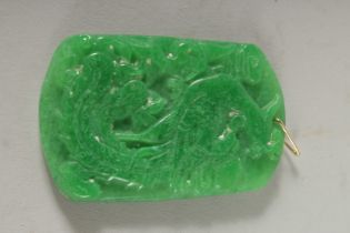 A CARVED JADE PENDANT with gold ring. 2.5ins.