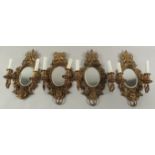 A GOOD SET OF FOUR GILDED TWO LIGHT WALL SCONCES with oval mirrored backs and lion rings. 16ins