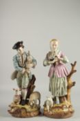 A PAIR OF SEVRES DESIGN PORCELAIN FIGURES of a man and a woman, sheep at her feet. 17ins high.