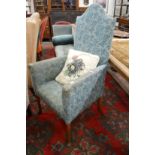 An upholstered high back armchair.