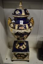 A large porcelain urn on stand decorated in Imari colours (faults).