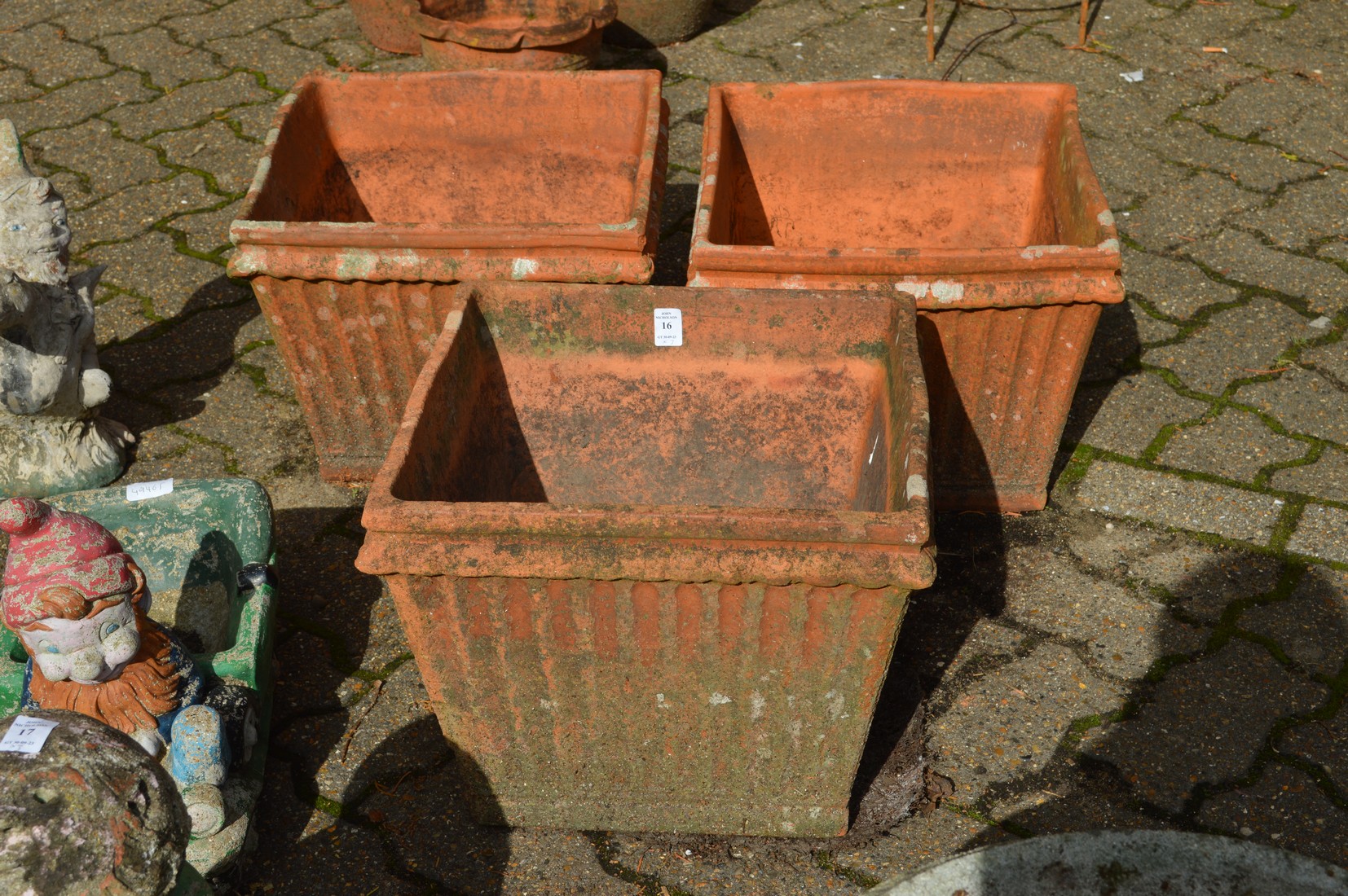 A set of three terracotta square shaped plant pots.