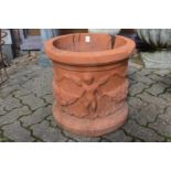 A large circular terracotta plant pot with moulded decoration.