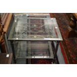A heavy wrought iron square shaped two tier coffee table with glass top and under tier.
