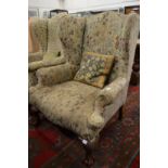 Floral upholstered Georgian style wing armchair on cabriole legs.