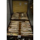 Two boxes containing a quantity of plated fish knives and forks.