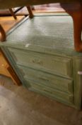 A green painted rattaned three drawer chest.