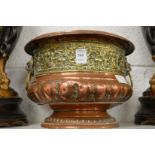 An embossed copper and brass pedestal jardiniere with lion mask handles.