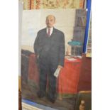 Russian School, Full length portrait of Lenin holding a newspaper standing by a table, oil on