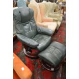 A green leather upholstered reclining swivel armchair with matching foot stool.