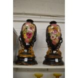 A pair of floral decorated pottery vases on stands.