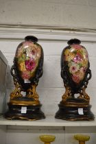 A pair of floral decorated pottery vases on stands.