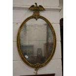A gilt framed oval mirror with eagle cresting.
