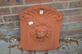 A terracotta wall fountain plaque with lion mask detail.