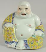 A LARGE CHINESE FAMILLE JAUNE PORCELAIN LAUGHING BUDDHA, the deity modelled in the seated position