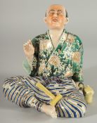 A JAPANESE KUTANI PORCELAIN FIGURE, of a seated man with a cat at his side, 18cm high.