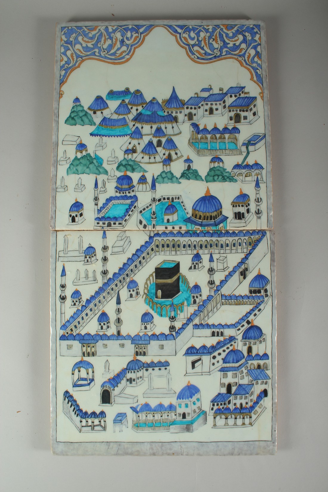 A TWO-PIECE OTTOMAN TURKISH IZNIK POTTERY TILE DEPICTING MECCA, each tile 30cm square, (2).