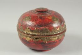 A SMALL RED LACQUERED WOOD CIRCULAR BOX, with decorative brass mounts, 14cm diameter.