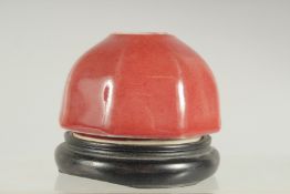A SMALL CHINESE COPPER RED PORCELAIN INK POT, on a fitted wooden stand.