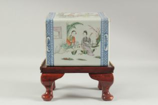 A CHINESE FAMILLE ROSE PORCELAIN PILLOW, and later wooden stand, painted with scenes of female