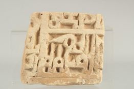 A 14TH CENTURY PERSIAN ILKHANID CARVED POTTERY TILE, with Kufic calligraphy, 15cm x 14cm.