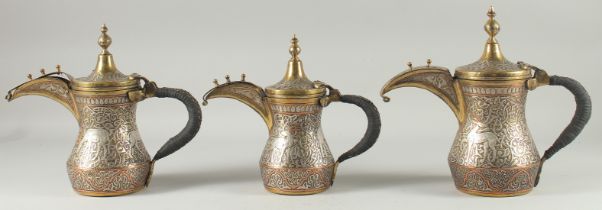 A FINE SET OF THREE EARLY 20TH CENTURY CAIROWARE ARAB SILVER AND COPPER INLAID BRASS COFFEE POTS, of