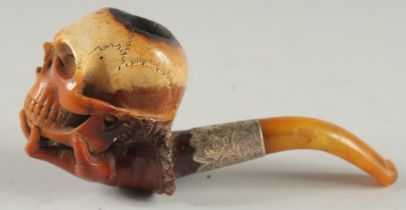 A MEERSCHAUM PIPE CARVED ON AS A HAND HOLDING A SKULL, 6cm long with silver band and curving amber