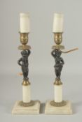 A PAIR OF BRONZE ORMOLU AND MARBLE CUPID CANDLESTICKS on square bases with shades. 10ins high.